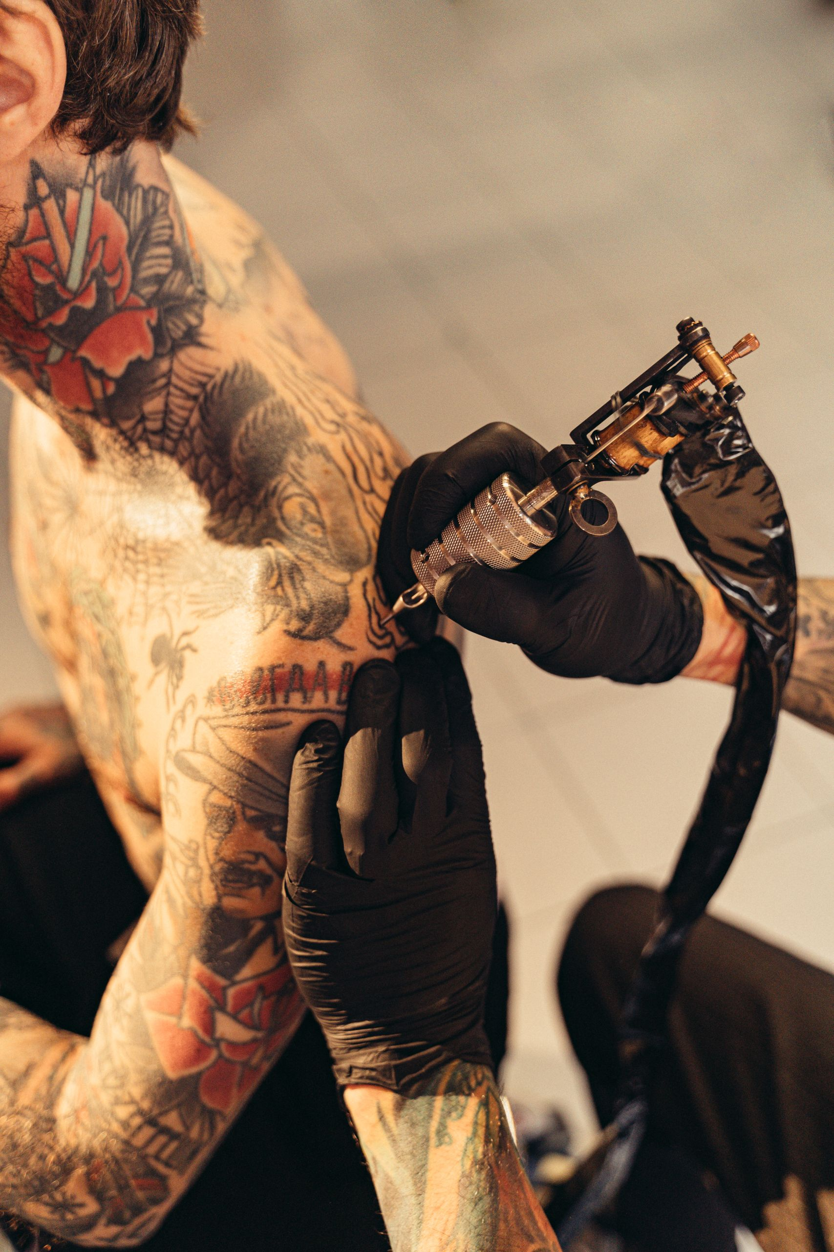 Tattoo artist skillfully etching detailed design on client's shoulder in studio.